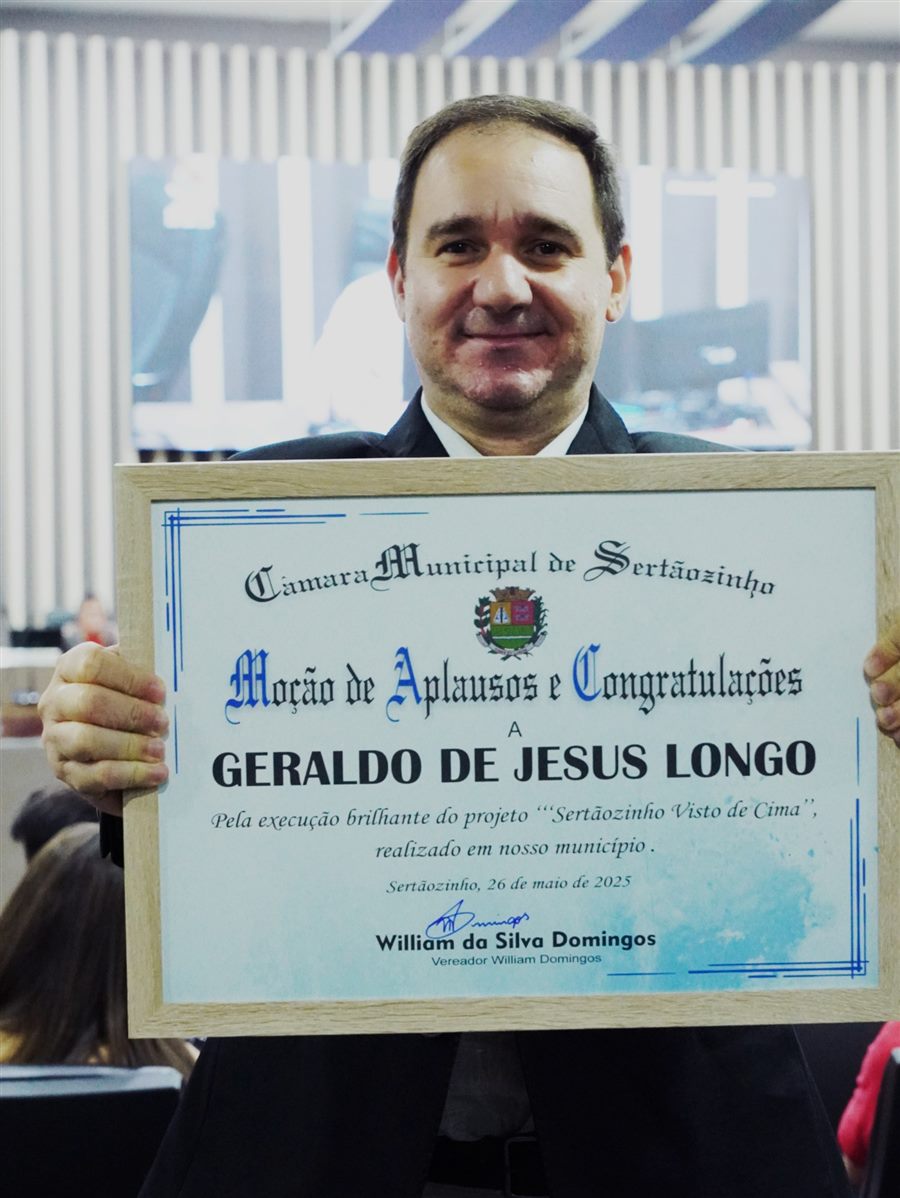 Jr Longo segurando o quadro da Moção de Aplausos e Congratulações da Câmara Municipal de Sertãozinho